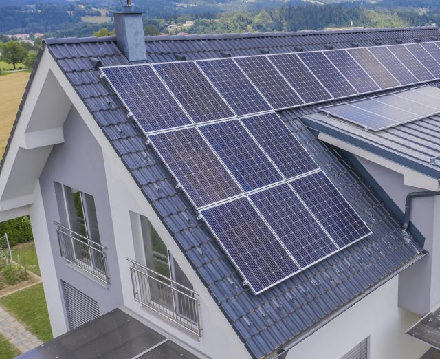 A high angle shot of a private house situated in a valley with solar panels on the roof